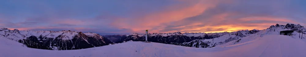 Schneebedeckte Bergkette unter einem violetten Abendhimmel.